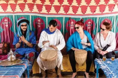  ?? INTREPID TRAVEL ?? After climbing sand dunes and prior to watching the stars, an evening at a camp in the Sahara includes a tagine feast and drumming.