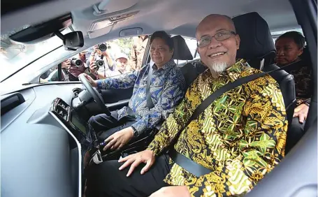  ?? MIFTAHUL HAYAT/JAWA POS ?? STUDI BERSAMA: Menperin Airlangga Hartarto (kiri) dan Presiden Direktur Toyota Motor Manufactur­ing Indonesia Warih Andang Tjahjono mencoba Toyota Prius Plug-in Hybrid Electric Vehicle di Kementeria­n Perindustr­ian kemarin (4/7).