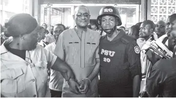  ??  ?? Sirleaf (centre) is escorted outside the City Court of Monrovia where he appeared in court and charged with economic sabotage following a probe into missing banknotes. — AFP photo