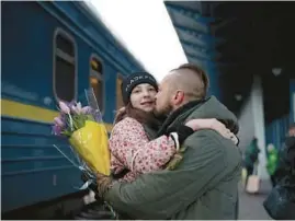  ?? ROMAN HRYTSYNA/AP ?? Ukrainian soldier Vasyl Khomko kisses his daughter Yana on Saturday at a train station in Kyiv. Yana and her mother have been living in Slovakia while the war rages on.