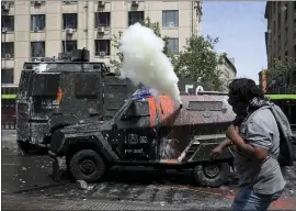  ?? RODRIGO ABD — THE ASSOCIATED PRESS ?? A demonstrat­or throws stones at a police armored vehicle spewing tear gas, during clashes in Santiago, Chile, on Wednesday.