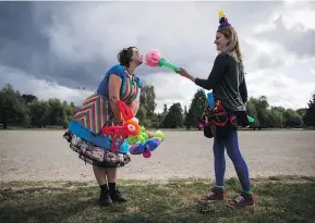  ?? DARRYL DYCK / THE CANADIAN PRESS ?? Face painter Ilea Wakelin, left, and balloon artist Lauren Preston joke around Monday during a protest against a proposed balloon ban in Vancouver’s parks.