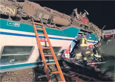  ??  ?? Rescuers work in the aftermath of the incident after a truck smashed through a barrier and struck a train near Turin