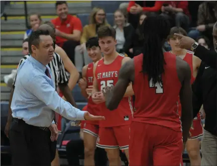  ?? KEN SWART — MEDIANEWS GROUP, FILE ?? Orchard Lake St. Mary’s head coach Todd Covert (left) and Marcus Webster (right) welcome JaVaughn Hannah (4) back to the bench in a game against Clarkston in December 2021. St. Mary’s may be without two of its best players in 2023due to a league transfer rule that’s being challenged by a lawsuit.