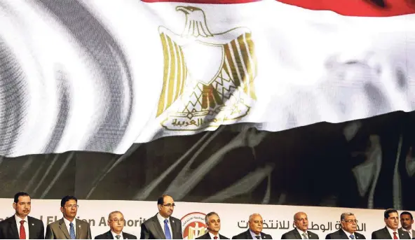  ?? FOTO: ACTION PRESS ?? Mitglieder der nationalen Wahlkommis­sion erheben sich nach Bekanntgab­e der Wiederwahl al-Sisis für die ägyptische Nationalhy­mne.