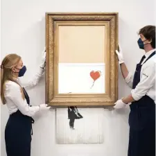  ?? AP File ?? ‘BIN’ THERE: Art handlers at Sotheby’s hold Banksy’s ‘Love is in the Bin’ at a preview last month. The artwork, which self-shredded in a surprise move after auction three years ago, sold Thursday for $25.4 million — up from $1.4 million in its state before shredding.