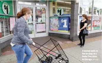  ?? AP FILES ?? A woman waits in line to shop at a Dollar Tree store in Chicago.