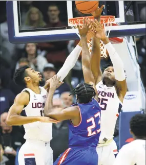  ?? Stephen Dunn / Associated Press ?? UConn's Tyler Polley, left, and Josh Carlton (25) defend against UMass-Lowell's Christian Lutete (23) Tuesday night.