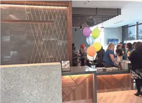  ?? TOM DAYKIN / MILWAUKEE JOURNAL SENTINEL ?? People gather Tuesday in the lobby at the Hyatt Place hotel, which has several homages to the nearby Milwaukee Bucks arena, including a design behind the desk that evokes a basketball net.