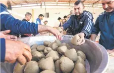  ?? ?? Volunteers prepare portions of the traditiona­l Libyan dish “Bazin”, which consists of a dough made with barley, water, and salt in the coastal city of Tajura east of Tripoli, to be distribute­d to needy families during the Muslim holy fasting month of Ramadan.