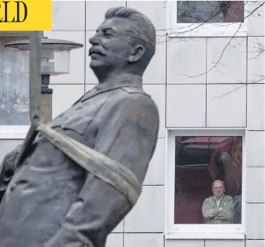  ?? JOHN MACDOUGALL / AFP / GETTY IMAGES ?? A resident watches as a statue of former Soviet dictator Josef Stalin is lifted by a crane in Berlin Tuesday. The statue stood for 15 minutes before being moved, to promote an exhibition in the German capital called Stalin, The Red God.