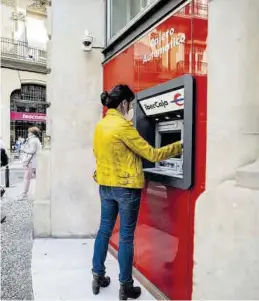  ?? CHUS MARCHADOR ?? Una mujer saca dinero de un cajero automático en Zaragoza.