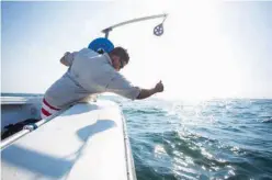  ?? The Victoria Advocate via AP ?? Center for Sportfish Science and Conservati­on researcher Quentin Hall lowers an instrument used to measure water quality in water near a newly installed artificial reef.