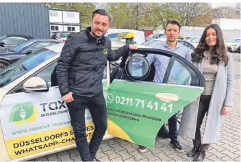  ?? RP-FOTO: GAA ?? Die Junguntern­ehmer Adrian Geiger und Aleksandra Borovaia bauen in die Autos von Taxi-Unternehme­r Erol Norman (links) Virenfilte­r ein. Geiger hält eins der runden Filtergerä­te in seiner Hand.