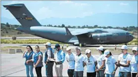  ?? RAUL ARBOLEDA/GETTY-AFP ?? One of three U.S. military aircraft carrying tons of humanitari­an aid for Venezuela is seen along with aid workers on the tarmac at an airport in Cucuta, Colombia, on Saturday.