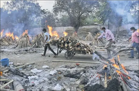  ?? THE ASSOCIATED PRESS ?? A worker carries wood on a hand cart as multiple funeral pyres of COVID-19victims burn at a crematoriu­m on the outskirts of New Delhi, India, May 1.