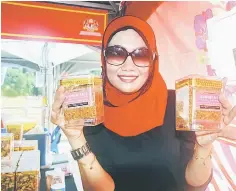  ??  ?? An entreprene­ur proudly shows the ‘Sarunding Halia and ‘Ikan Terubuk Masin’ she sells at her stall.