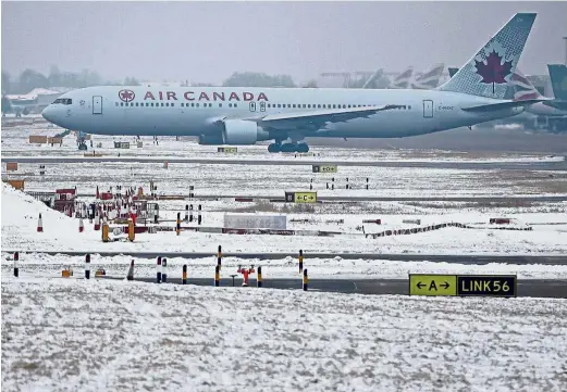  ??  ?? Not going
anywhere: An Air Canada flight remains grounded as the runway is covered with snow. — AFP