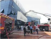  ?? AFP ?? Firefighte­rs and rescuers gather in front of the headquarte­rs of Libya’s National Oil Company in the capital Tripoli after it was attacked by masked gunmen