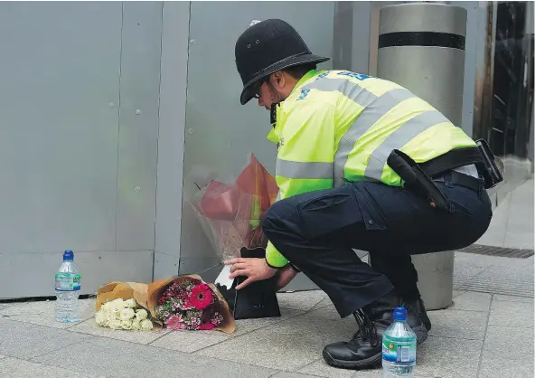  ?? — GETTY IMAGES ?? A police officer lays flowers from a well-wisher Sunday outside The Shard pub near London Bridge, scene of a terror attack late Saturday. Seven people, including a B.C. woman, were killed and 48 wounded by three men who drove a van onto a crowded...