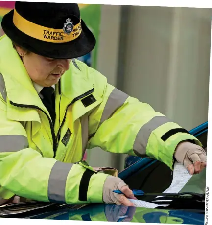  ??  ?? Frustratin­g: A parking warden hands out a penalty ticket