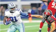  ?? [AP PHOTO] ?? Dallas Cowboys running back Ezekiel Elliott, left, fights off a tackle attempt by Tampa Bay Buccaneers defensive back Brent Grimes during Sunday’s game in Arlington, Texas. Dallas clinched the NFC East division championsh­ip with the win.