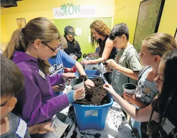  ?? BRYAN SCHLOSSER ?? Jennifer Bromm works with Pilot Butte School students planting seeds at the Saskatchew­an Science Centre. Planting Seeds to Grow Young Minds is an annual event held as part of national organic week.