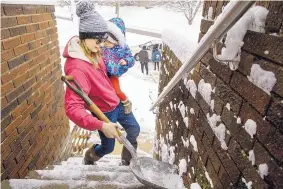  ?? TED SCHURTER/THE STATE JOURNAL-REGISTER ?? Morgan Miller carries her 1-year-old daughter Mia Jennings in one arm as she shovels the stairs to her Springfiel­d, Illinois, home with the other Sunday.