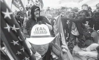  ?? John Minchillo / Associated Press ?? Violent insurrecti­onists loyal to then-President Donald Trump try to break through a police barrier at the Capitol on Jan 6. Many of those who stormed the Capitol cited lies about the election.