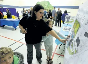  ?? CLIFFORD SKARSTEDT/EXAMINER ?? Chantelle Clarke and her daughter Paige, a Grade 3 student at Armour Heights Public School, look at plans during an open house held at King George Public School in East City on Thursday night to show the families of students the plans for the new...