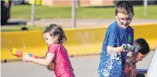  ?? DANIEL BROWN/LOCAL JOURNALISM REPORTER ?? Kolin and Mya Beaton, both students at Westwood Primary School in Cornwall, take part in a squirt gun war with their teachers on June 22. Behind is their mother who’s helping reload their squirt guns.