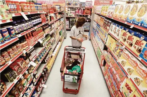  ??  ?? Alicia Ortiz peruses the cereal aisle as her daughter, Aaliyah Garcia, catches a nap in the shopping cart at a Family Dollar store in Waco. Up and down supermarke­t aisles, rows of perfectly placed products reflect calculated deliberati­ons aimed at...