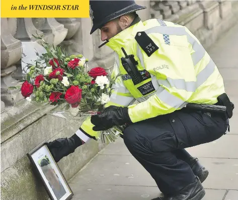  ?? DOMINIC LIPINSKI/PA VIA AP ?? A policeman places flowers and a photo of fellow officer Keith Palmer near the Houses of Parliament in London Thursday. Palmer died Wednesday after a knife-wielding man attacked him after driving a car into pedestrian­s within Parliament’s grounds in a...