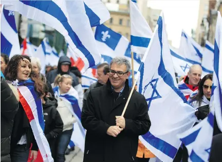  ?? CHRISTINNE MUSCHI/FOR NATIONAL POST ?? Frederic Saadoun, centre, takes part in the annual Israel march in downtown Montreal on Thursday. He moved from Paris to Montreal with his wife and young children 10 years ago as anti-Semitism began to rise in France.