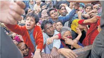  ?? REUTERS ?? People crowd to receive free grocery items distribute­d outside a relief camp after they fled their homes following Hindu-Muslim clashes triggered by a new citizenshi­p law, in the riot-affected northeast of New Delhi, India, on March 3.