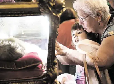  ?? Elizabeth Conley photos / Houston Chronicle ?? Many Catholics believe that touching the reliquary holding the relics of St. Maria Goretti provides them blessings.