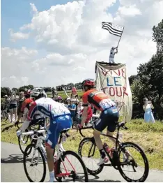  ?? Foto: afp ?? Die Begeisteru­ng ist riesig: „Es lebe die Tour“steht auf der Plastikpla­ne vor dem Turm, auf dem ein Radsport Fan die Flagge der Bretagne schwenkt.