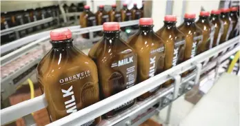  ?? ANTONIO PEREZ/CHICAGO TRIBUNE ?? Glass milk bottles move through a bottling line at Oberweis Dairy in North Aurora in 2017.