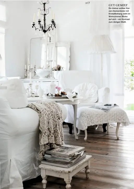 ??  ?? GUT GEMIXT Ein kleiner antiker Kerzen-Deckenlüst­er mit Kristallbe­hang zieht im Wohnzimmer Blicke auf sich – ein Kontrast zum übrigen Weiß.