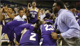  ?? (Arkansas Democrat-Gazette/Thomas Metthe) ?? England Coach Trent Morgan (right) celebrates with players after the Lions’ 68-57 victory over Earle in the Class 2A boys basketball state championsh­ip game Thursday at Bank OZK Arena in Hot Springs. See more photos at arkansason­line.com/313boys2a/