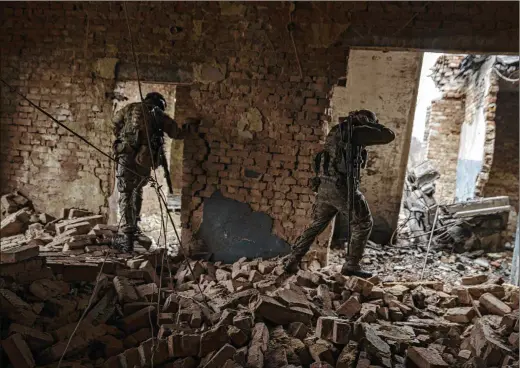  ?? PHOTOS BY TYLER HICKS/NEW YORK TIMES ?? Ukrainian soldiers with the 79th Air Assault Brigade move through a damaged building in an area of Marinka, a town that does not really exist anymore, abandoned by roughly 9,000 prewar residents. Some of the scenes from the front show not much has changed in close combat since World War I.