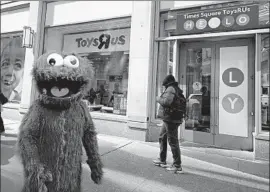  ?? Timothy A. Clary AFP/Getty Images ?? TOYS R US confirmed Thursday that it will shut all of its U.S. stores. Above, a “Sesame Street” character waits outside the retail giant’s New York City location.