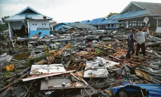  ?? Rifki / Associated Press ?? Indonesian men survey the damage in Palu, Indonesia, after a powerful earthquake triggered a tsunami. Hundreds of people were killed, and the death toll is expected to rise.