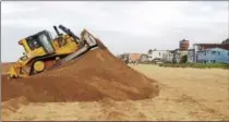  ?? AP PHOTO/MICHAEL R. BLOOD, FILE ?? In this 2015 file photo, a bulldozer piles sand into a high berm to protect homes along Sunset Beach in Huntington Beach, Calif. The state’s Ocean Protection Council decided weeks ago to update its sea-rise guidance for state and local government­s.
