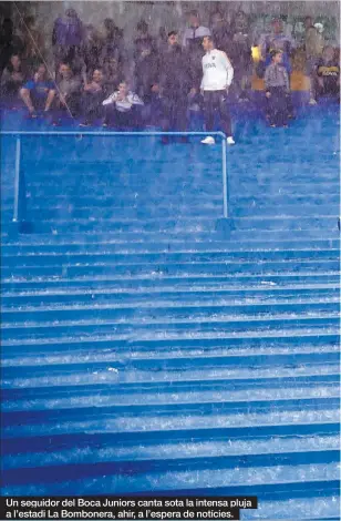  ??  ?? Un seguidor del Boca Juniors canta sota la intensa pluja a l’estadi La Bombonera, ahir, a l’espera de notícies.