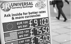  ??  ?? Pedestrian­s walk past a board diplaying the price of Euro and US dollars against British pound Sterling, outside a currency exchange store in central London. The Brexit-hit British pound threatens to reach parity with the euro – and is already worth...