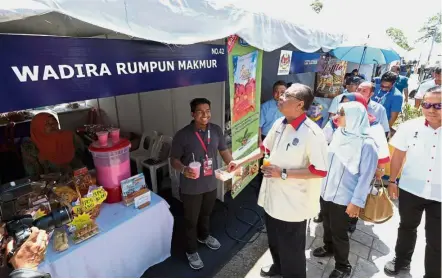  ??  ?? Browsing around: Ismail Sabri trying samples at a food stall during a walkabout at the Rural Entreprene­ur Mini Carnival. — Bernama