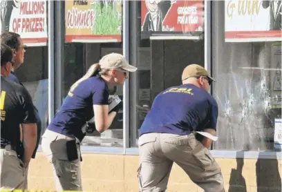  ?? USMAN UKALIZAI/AFP VIA GETTY IMAGES ?? FBI agents look at bullet holes Sunday at the Tops Friendly Market grocery in Buffalo, New York.