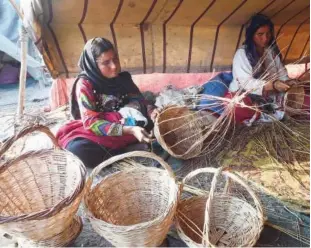  ??  ?? INEXPENSIV­E STORAGE SOLUTION: Pakistani gypsies weave handmade baskets in their makeshift tent on the outskirts of Lahore on Saturday.