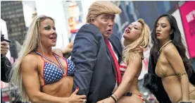  ?? — AFP ?? A Donald Trump lookalike poses with bikini-clad women in New York City on Tuesday. Organised by British spoof photograph­er Alison Jackson, the stunt also featured women holding placards reading “I am a nasty woman”, among other things, in protest...